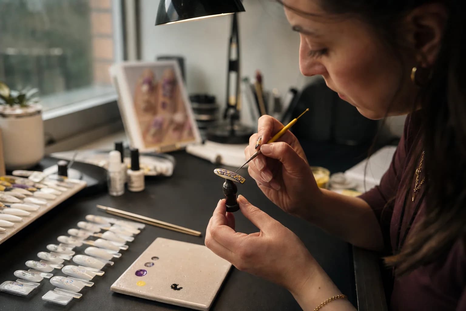 An independent artist hand-painting a press-on nail in her studio